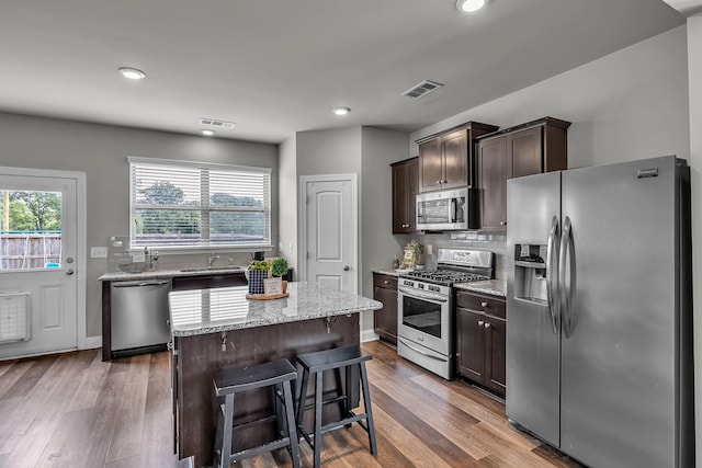 1010 Keeneland Dr, Spring Hill, TN 37174 - kitchen featuring appliances with stainless steel finishes, a sink, dark brown cabinetry, decorative backsplash, and light stone counters