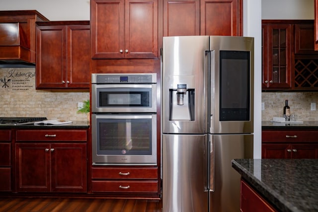 1820 Lanceford Ct, Franklin, TN 37067 - kitchen with appliances with stainless steel finishes, reddish brown cabinets, dark stone countertops, dark wood finished floors, and tasteful backsplash