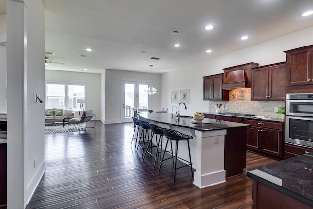 1820 Lanceford Ct, Franklin, TN 37067 - kitchen featuring premium range hood, appliances with stainless steel finishes, dark wood-style flooring, a breakfast bar area, and a center island with sink