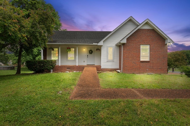 862 College St, Portland, TN 37148 - view of front of house with covered porch, a yard, a shingled roof, and brick siding