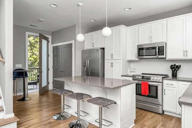 2120 Herman St Unit 9, Nashville, TN 37208 - kitchen featuring stainless steel appliances, light wood-type flooring, white cabinets, a breakfast bar area, and recessed lighting