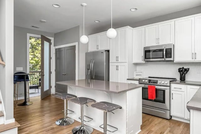 2120 Herman St Unit 8, Nashville, TN 37208 - kitchen with appliances with stainless steel finishes, light wood-style floors, white cabinetry, a breakfast bar area, and a kitchen island