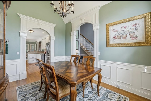 5122 Stonewood Dr, Smyrna, TN 37167 - dining area featuring arched walkways, ornate columns, a wainscoted wall, wood finished floors, and a decorative wall