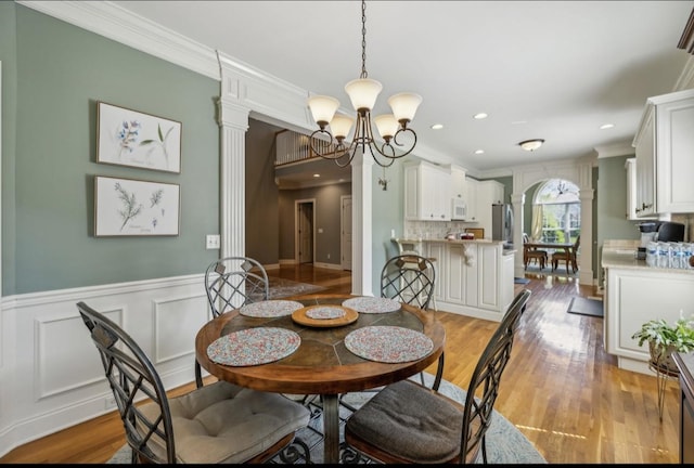 5122 Stonewood Dr, Smyrna, TN 37167 - dining area with a chandelier, ornamental molding, light wood finished floors, ornate columns, and a wainscoted wall