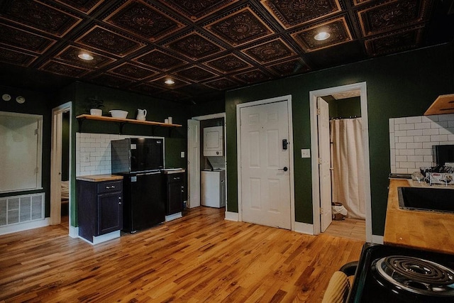 800 Riverside Dr, Columbia, TN 38401 - kitchen with black appliances, stacked washing machine and dryer, light wood-type flooring, open shelves, and an ornate ceiling
