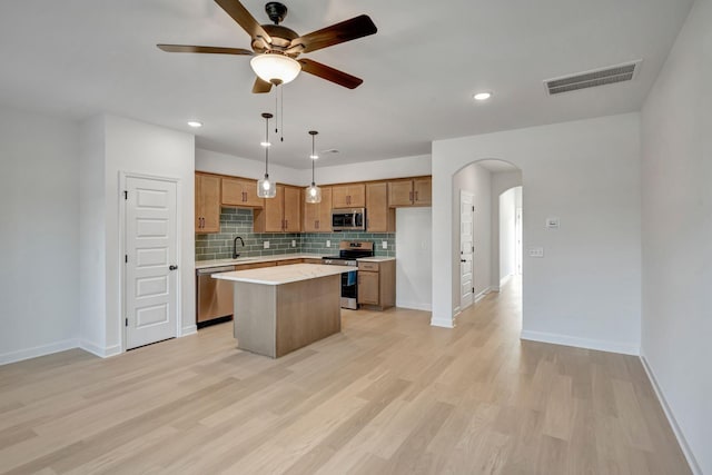 116 Beignet Aly, Hendersonville, TN 37075 - kitchen featuring appliances with stainless steel finishes, arched walkways, a center island, light countertops, and tasteful backsplash
