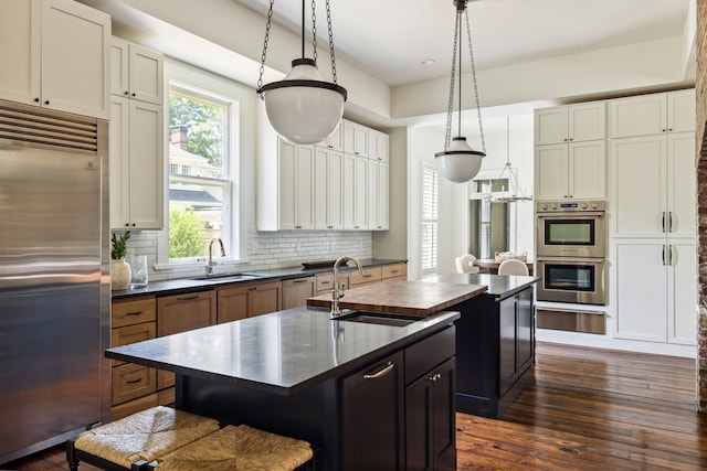 1051 W Main St, Franklin, TN 37064 - kitchen with appliances with stainless steel finishes, dark countertops, a warming drawer, a center island with sink, and a sink