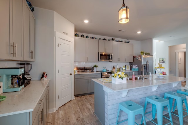308 Whisper Wood Way, Lebanon, TN 37087 - kitchen with appliances with stainless steel finishes, backsplash, a breakfast bar area, light wood-style floors, and gray cabinets