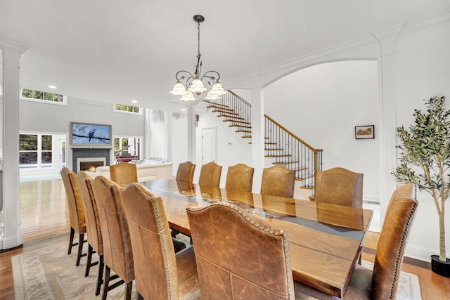 6948 Whispering Oaks Dr, Springfield, TN 37172 - dining room featuring wood finished floors, a chandelier, stairway, a lit fireplace, and ornate columns