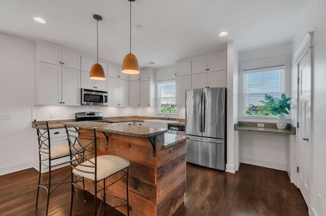 801 Lancaster Way, Nashville, TN 37212 - kitchen featuring appliances with stainless steel finishes, baseboards, dark wood-type flooring, white cabinetry, and a breakfast bar area