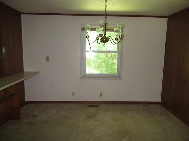 107 Jay Cir, Clarksville, TN 37040 - unfurnished dining area featuring a chandelier, carpet flooring, wood walls, baseboards, and a textured ceiling