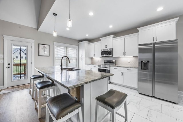 1103 Chagford Dr, Clarksville, TN 37043 - kitchen featuring appliances with stainless steel finishes, a sink, white cabinets, stone counters, and a center island with sink