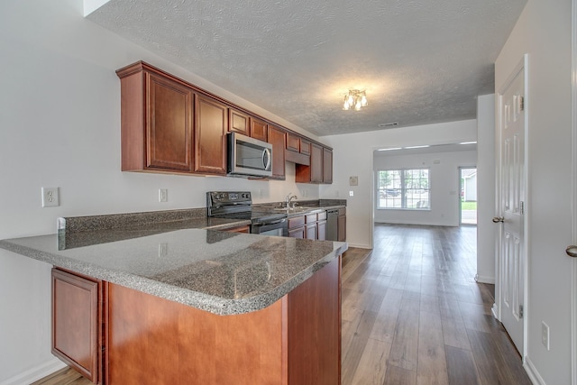 2026 Caladonia Way, Smyrna, TN 37167 - kitchen featuring stainless steel appliances, a textured ceiling, brown cabinetry, a peninsula, and wood finished floors