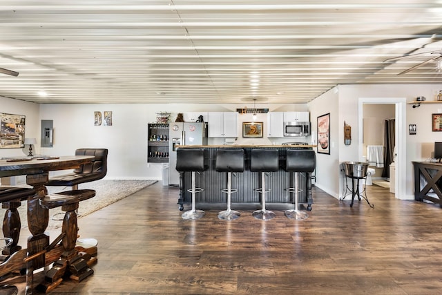 211 Hood St, Dover, TN 37058 - kitchen with stainless steel microwave, a kitchen bar, white cabinets, dark wood-style floors, and a kitchen island