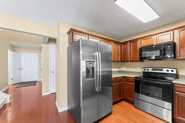 1036 Harold Lee Dr, Smyrna, TN 37167 - kitchen featuring stainless steel appliances, light countertops, light wood-style flooring, brown cabinets, and baseboards