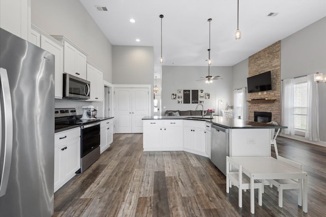 720 Jersey Dr, Clarksville, TN 37043 - kitchen featuring stainless steel appliances, a sink, dark countertops, open floor plan, and a large fireplace