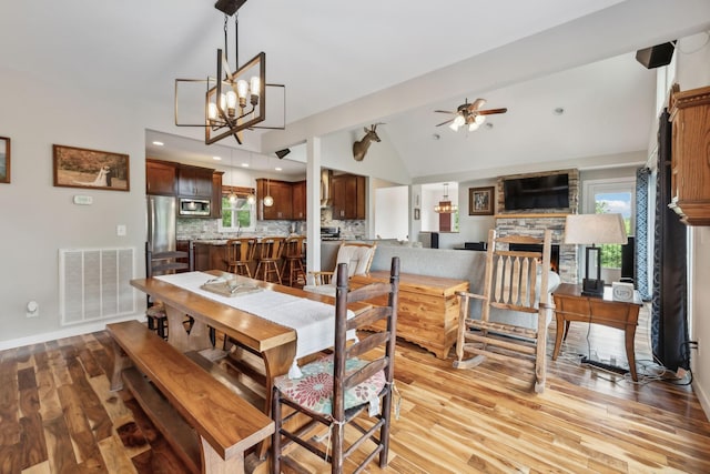 225 Ferguson Creek Rd, Sparta, TN 38583 - dining room with vaulted ceiling, light wood finished floors, a stone fireplace, a ceiling fan, and a chandelier
