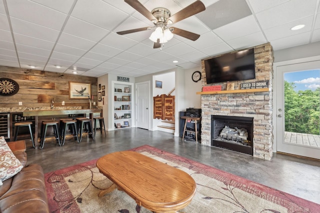 225 Ferguson Creek Rd, Sparta, TN 38583 - living room with finished concrete floors, a ceiling fan, a drop ceiling, a fireplace, and wood walls