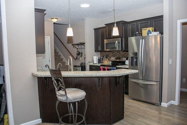 112 Read Tavern Rd, Hendersonville, TN 37075 - kitchen featuring appliances with stainless steel finishes, a breakfast bar area, decorative backsplash, light wood finished floors, and a peninsula