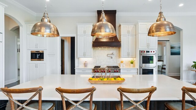 4740 Edwardian Trce, Franklin, TN 37067 - kitchen featuring double oven, arched walkways, a breakfast bar area, tasteful backsplash, and a large island with sink