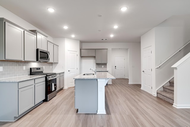316 Deacon Ln, White House, TN 37188 - kitchen with stainless steel appliances, gray cabinets, light wood finished floors, a sink, and decorative backsplash