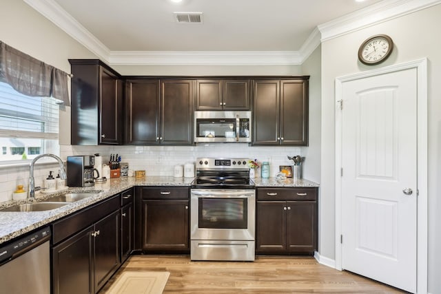 319 Petunia Dr, Smyrna, TN 37167 - kitchen with stainless steel appliances, a sink, light stone countertops, light wood finished floors, and dark brown cabinetry