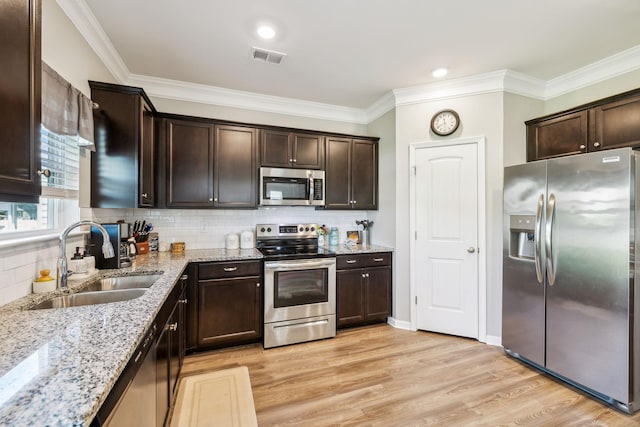 319 Petunia Dr, Smyrna, TN 37167 - kitchen featuring stainless steel appliances, a sink, dark brown cabinetry, ornamental molding, and light wood-type flooring