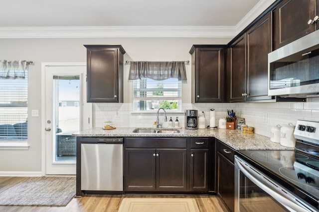 319 Petunia Dr, Smyrna, TN 37167 - kitchen with appliances with stainless steel finishes, a sink, light stone countertops, light wood finished floors, and crown molding