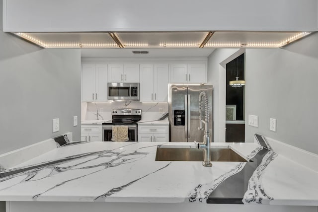 212 Post Creek Rd, Nashville, TN 37221 - kitchen with stainless steel appliances, white cabinetry, tasteful backsplash, light stone counters, and a sink
