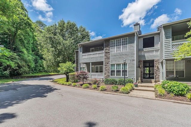 212 Post Creek Rd, Nashville, TN 37221 - view of front of house featuring a chimney, stone siding, and a balcony