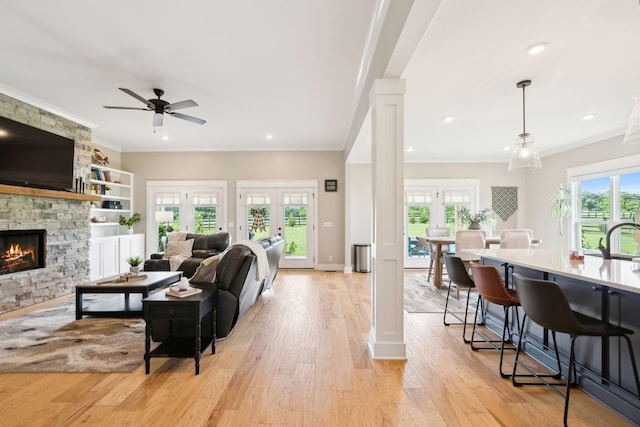 11769 Milton St, Milton, TN 37118 - living room with decorative columns, a stone fireplace, ornamental molding, light wood-type flooring, and a ceiling fan