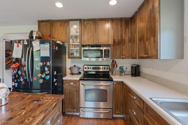 287 Rack Clayton Rd, Hohenwald, TN 38462 - kitchen featuring appliances with stainless steel finishes, brown cabinets, recessed lighting, glass insert cabinets, and dark wood-style flooring