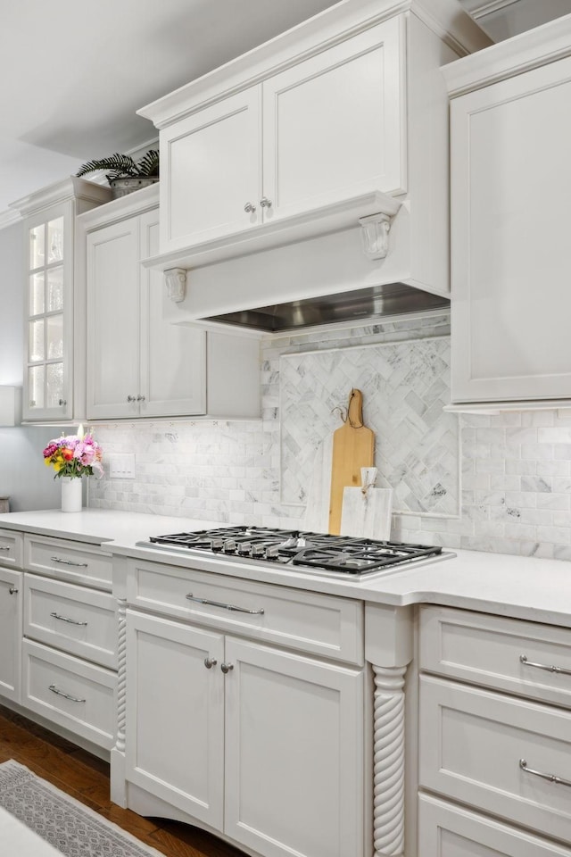 1018 Buddleia Ln, Franklin, TN 37067 - kitchen with white cabinetry, light countertops, decorative backsplash, stainless steel gas stovetop, and glass insert cabinets