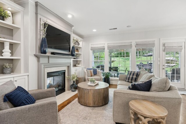 1018 Buddleia Ln, Franklin, TN 37067 - living area with ornamental molding, healthy amount of natural light, wood finished floors, a fireplace, and built in shelves