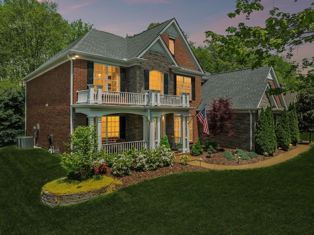 1018 Buddleia Ln, Franklin, TN 37067 - colonial-style house featuring a balcony, covered porch, stone siding, a front lawn, and roof with shingles