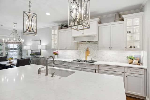 1018 Buddleia Ln, Franklin, TN 37067 - kitchen featuring a sink, a chandelier, stainless steel gas stovetop, crown molding, and white cabinetry