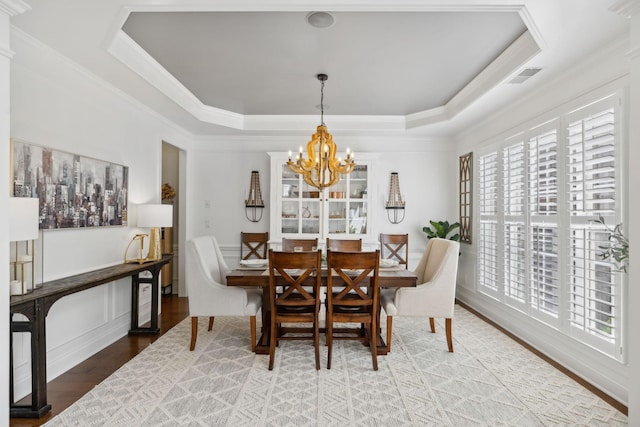 1018 Buddleia Ln, Franklin, TN 37067 - dining room featuring a chandelier, wood finished floors, ornamental molding, a raised ceiling, and a decorative wall