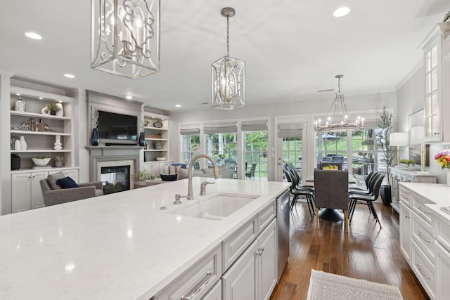 1018 Buddleia Ln, Franklin, TN 37067 - kitchen with a chandelier, a sink, a glass covered fireplace, dark wood-style flooring, and white cabinets