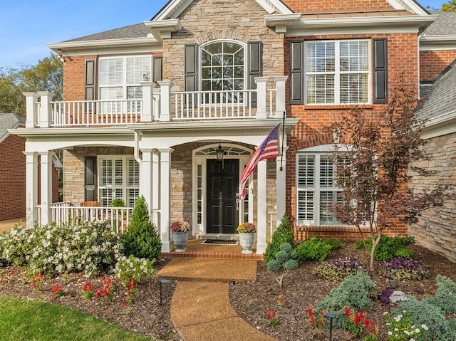 1018 Buddleia Ln, Franklin, TN 37067 - doorway to property with a balcony, stone siding, a porch, brick siding, and a shingled roof