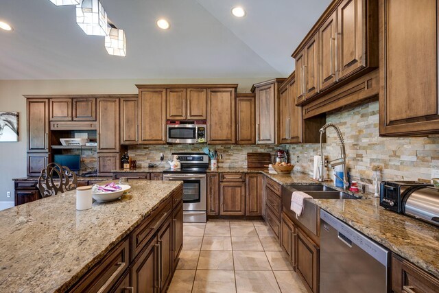 2290 Osburn Rd, Arrington, TN 37014 - kitchen featuring appliances with stainless steel finishes, lofted ceiling, backsplash, light stone counters, and brown cabinetry