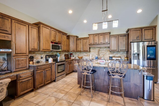 2290 Osburn Rd, Arrington, TN 37014 - kitchen featuring stainless steel appliances, lofted ceiling, a breakfast bar area, decorative backsplash, and light stone counters