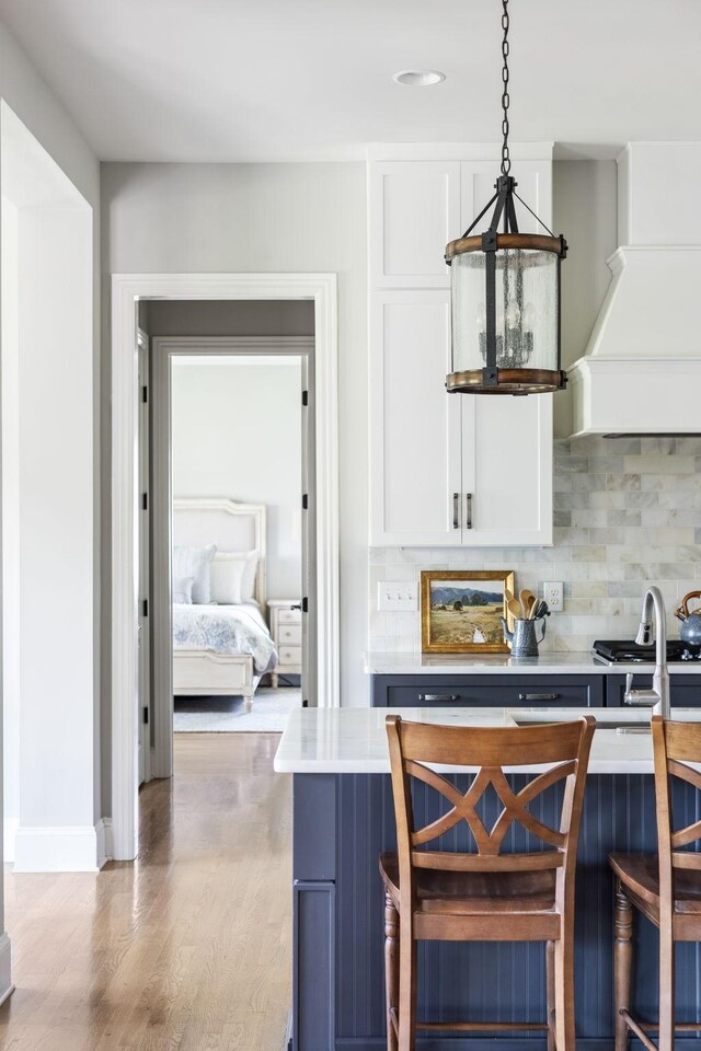 4136 Banner Square Ln, Arrington, TN 37014 - kitchen with light countertops, decorative backsplash, light wood finished floors, custom exhaust hood, and white cabinets