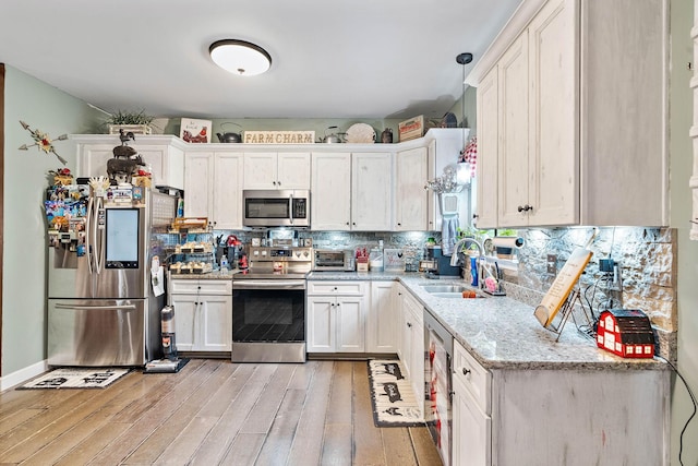 2328 C C C Rd, Dickson, TN 37055 - kitchen with stainless steel appliances, a sink, light wood finished floors, white cabinetry, and backsplash