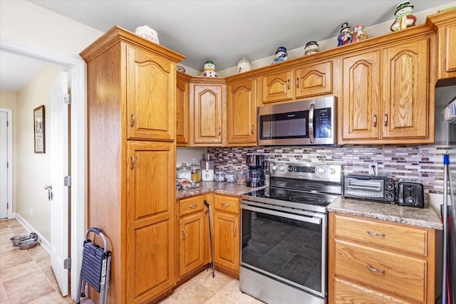 4190 Tanyard Hill Rd, Lynchburg, TN 37352 - kitchen featuring stainless steel appliances, decorative backsplash, light tile patterned floors, and brown cabinets