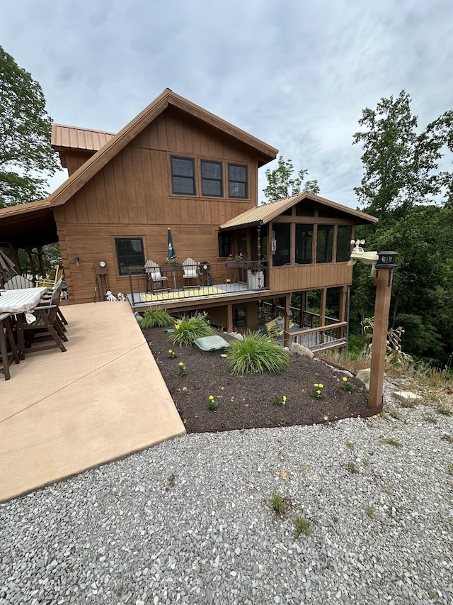 225 Bill Hunter Rd, Celina, TN 38551 - rear view of house featuring a sunroom, a patio, metal roof, board and batten siding, and driveway