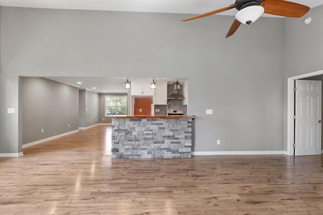 1054 Cragfront Est Loop, Gallatin, TN 37066 - unfurnished living room featuring a high ceiling, a ceiling fan, light wood finished floors, baseboards, and a sink