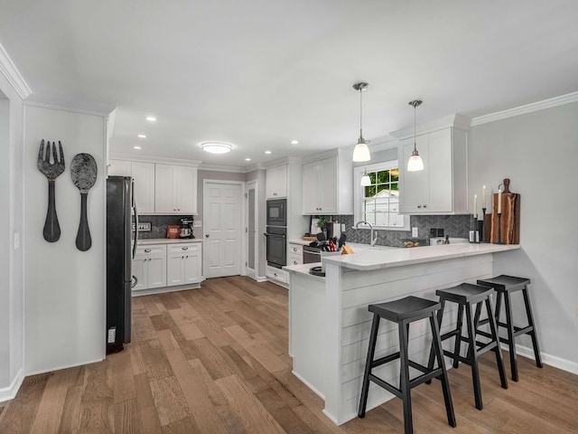 7119 Littlejohn Ln, Fairview, TN 37062 - kitchen with black appliances, a peninsula, light wood-style floors, white cabinetry, and ornamental molding