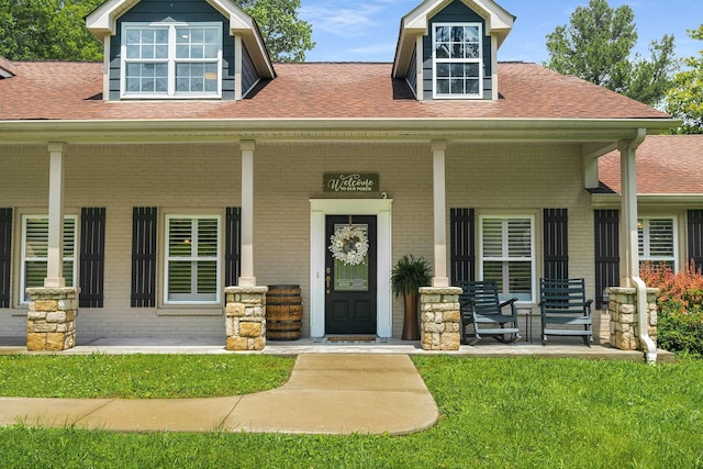 7119 Littlejohn Ln, Fairview, TN 37062 - doorway to property featuring covered porch, brick siding, a shingled roof, and a lawn