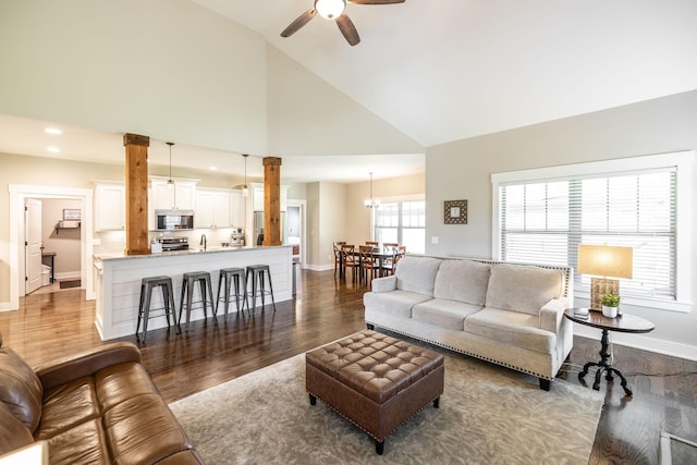 725B N Russell St, Portland, TN 37148 - living area featuring dark wood-style floors, ceiling fan, high vaulted ceiling, baseboards, and decorative columns