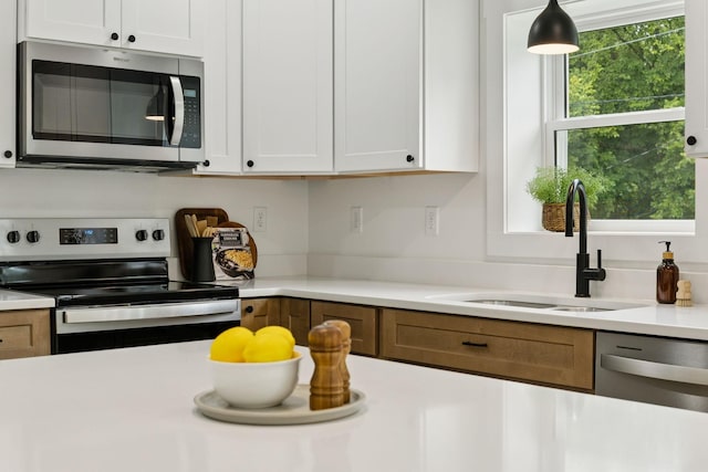 1775 Hayshed Rd, Charlotte, TN 37036 - kitchen with stainless steel appliances, light countertops, white cabinetry, and hanging light fixtures